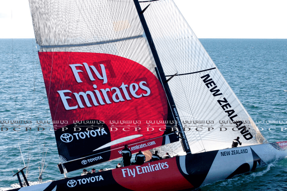 Custom-branded sail with a vibrant logo displayed on a sailboat, cutting through the water during a sunny day